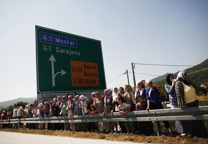 Bosnian's watch trucks carrying 520 coffins of newly identified victims of the 1995 Srebrenica massacre in Podlugovi, July 9, 2012. The bodies of the recently identified victims will be transported to the memorial centre in Potocari where they will be buried on July 11 marking the 17th anniversary of the massacre in which Bosnian Serb forces commanded by Ratko Mladic killed up to 8,000 Muslim men and boys and buried them in mass graves. REUTERS/Dado Ruvic (BOSNIA AND HERZEGOVINA - Tags: CIVIL UNREST POLITICS ANNIVERSARY) Published: Čec. 9, 2012, 11:07 dop.