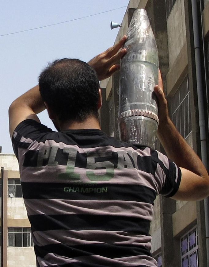 A Free Syrian Army member carries an unexploded shell, which they say belong to Syrian President Bashar al-Assad's forces, to a field in Aleppo July 29, 2012. REUTERS/Obeida Al Naimi (SYRIA - Tags: CIVIL UNREST MILITARY POLITICS CONFLICT) Published: Čec. 29, 2012, 5:13 odp.