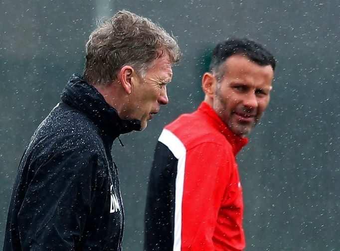 Manchester United's manager Moyes walks past Giggs during a training session at the club's Carrington training complex in Manchester