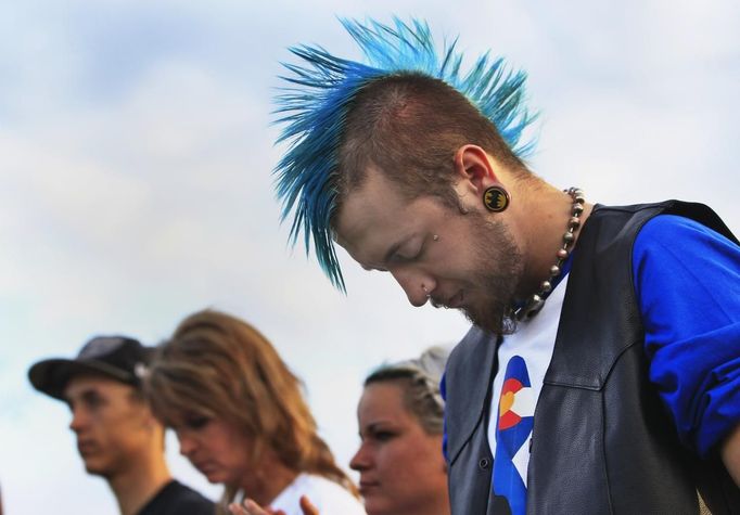 Hunter Furrow bows his head during a vigil for victims behind the theatre where a gunman opened fire last Friday on moviegoers in Aurora, Colorado July 22, 2012. Residents of a Denver suburb mourned their dead on Sunday from a shooting rampage by a "demonic" gunman who killed 12 people and wounded 58 after opening fire at a cinema showing the new Batman movie. President Barack Obama headed to Aurora, on Sunday to meet families grieving their losses in Friday's mass shooting that has stunned the nation and rekindled debate about guns and violence in America. REUTERS/Shannon Stapleton (UNITED STATES - Tags: DISASTER SOCIETY CIVIL UNREST) Published: Čec. 23, 2012, 1:20 dop.