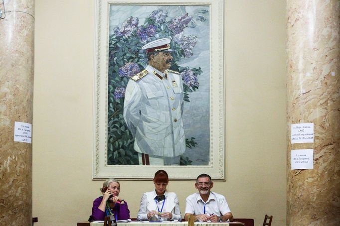 Úředníci volební komise čekají na voliče ve volební místnosti během voleb gubernátora a rady oblasti, nad nimiž je portrét Josifa Stalina, Volgograd, 2019