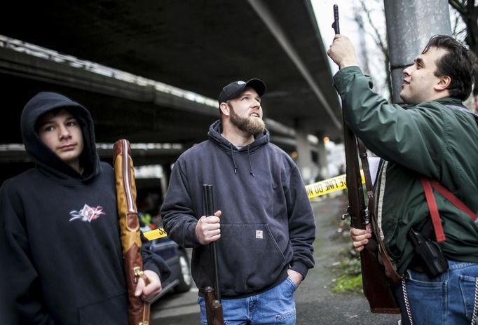 Derek Chauran (R) looks over the rifle he brought from someone after the Seattle Police Department buyback event ran out of gift cards in Seattle, Washington January 26, 2013. Participants received up to a $100 gift card in exchange for working handguns, shotguns and rifles, and up to a $200 gift card for assault weapons. The event lasted from 9 a.m. until shortly after noon, after the event ran out of $80,000 worth of gift cards. REUTERS/Nick Adams (UNITED STATES - Tags: POLITICS CIVIL UNREST) Published: Led. 27, 2013, 1:08 dop.