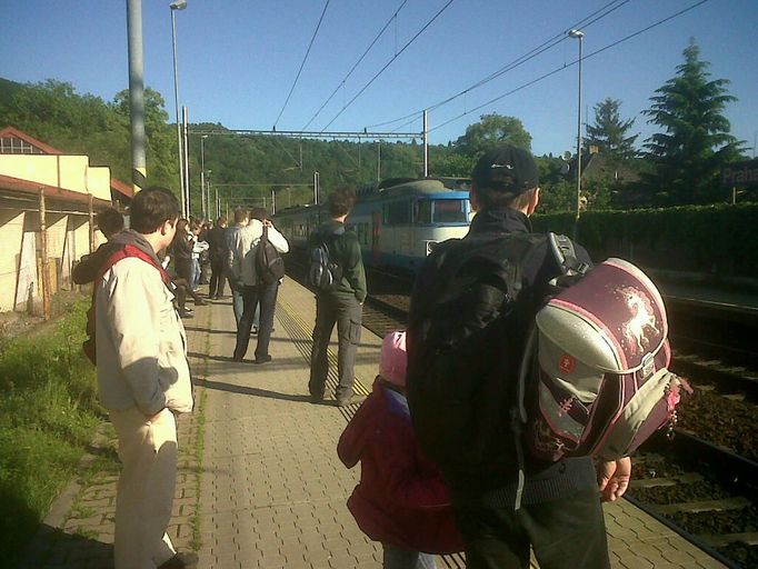 Na zastávce Praha - Sedlec čeká ráno na vlak obvykle do deseti lidí. Dnes je to hrubým odhadem tak patnáctkrát víc. Všichni mají hlavy otočené směrem k Roztokům a vyhlíží vlak, který má už 15 minut zpoždění.