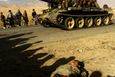 Afghánští bojovníci projíždějí na tanku T-62 kolem mrtvých těl. Snímek byl pořázen na silnici 3 km severně od Kábulu. 13. listopad 2001.