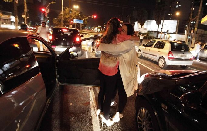 A member of the Traffic Psychologists (R) hugs a driver while performing along a road in Sao Paulo July 23, 2012. Traffic Psychologists is a non-profit non-governmental organization which aims to humanize traffic and reduce the level of stress caused to drivers. Sao Paulo has more than 7 million vehicles, according to figures from the state transport authority Detran. Picture taken July 23, 2012. REUTERS/Nacho Doce (BRAZIL - Tags: TRANSPORT SOCIETY) Published: Čec. 24, 2012, 7:19 dop.