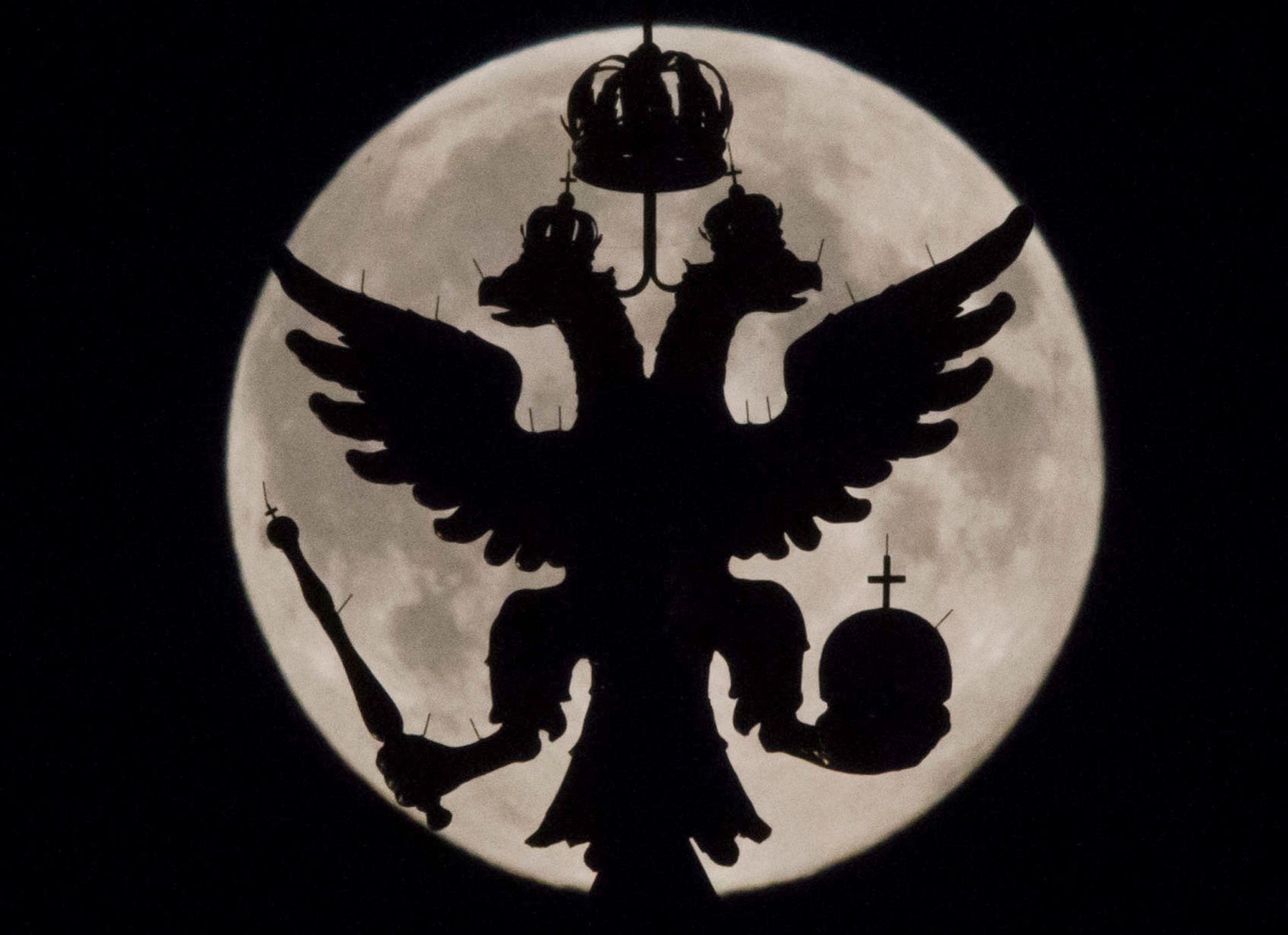 A two-headed eagle, the national symbol of Russia, is seen in front of the supermoon as it rises over the towers of Historical Museum in Moscow