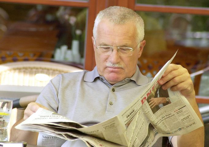 Prezident republiky Václav Klaus studuje denní tisk na terase golfového hřiště během své dovolené v Karlových Varech. 12.08.2003