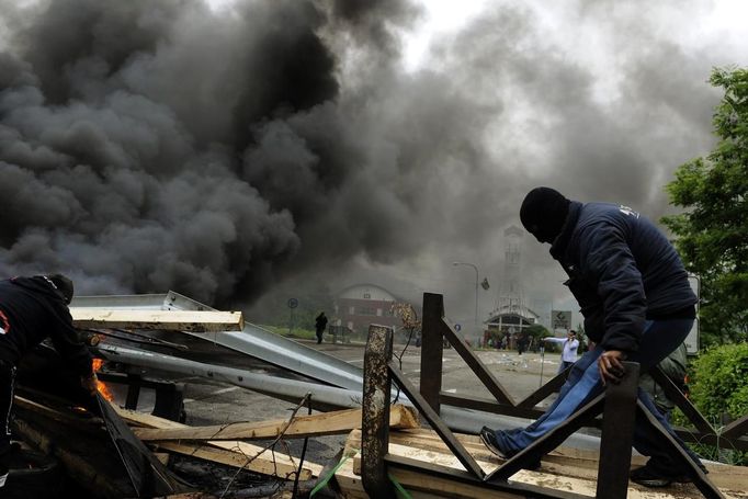 A coal miner makes a barricade next to burning tires in front of the main gate of the "Pozo Santiago" mine in Caborana, near Oviedo, northern Spain June 18, 2012. Spanish coal mining unions are taking part in a general strike in northern Spain mining areas to protest against government action to cut coal subsidies. REUTERS/Eloy Alonso (SPAIN - Tags: CIVIL UNREST BUSINESS EMPLOYMENT ENERGY) Published: Čer. 18, 2012, 1:10 odp.