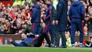 Manchester United manager Louis van Gaal lies on the side of the pitch to demonstrate a foul to the fourth official Mike Dean