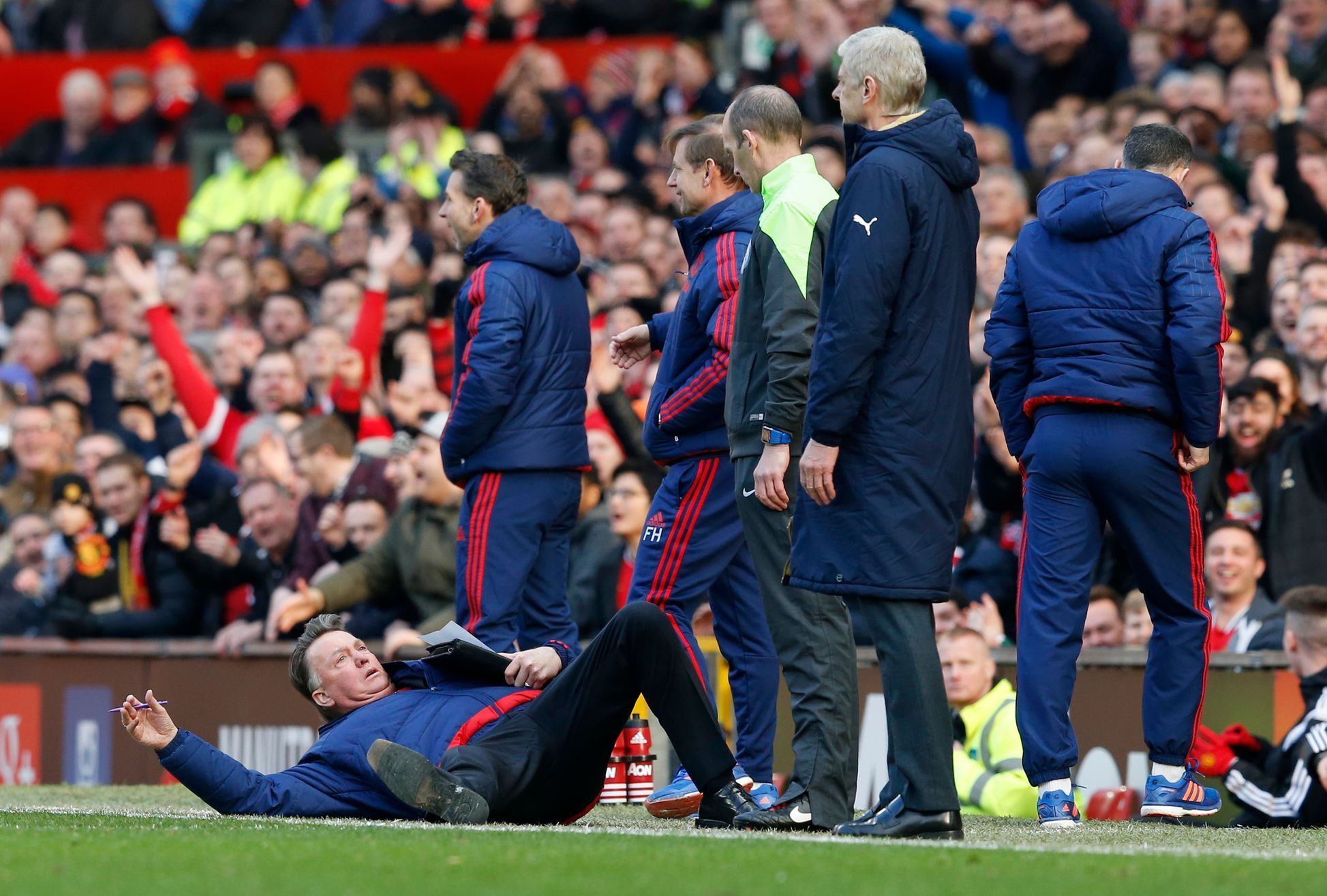 Manchester United manager Louis van Gaal lies on the side of the pitch to demonstrate a foul to the fourth official Mike Dean