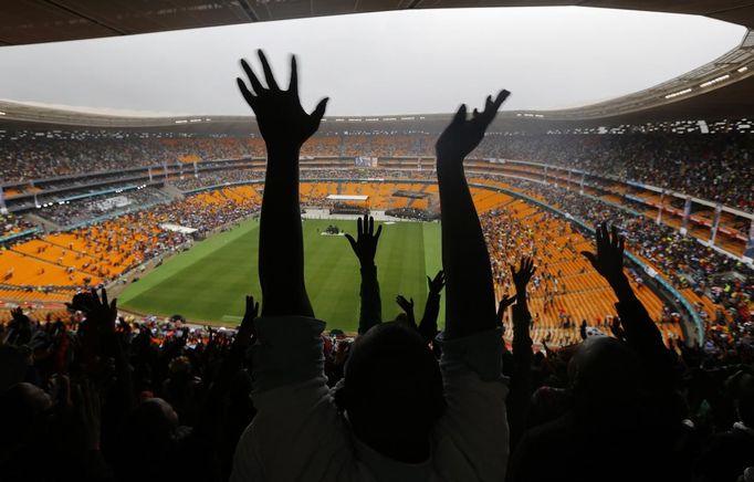 Mourners wave during the national memorial service for former South African President Nelson Mandela at the First National Bank Stadium, also known as Soccer City, in Johannesburg December 10, 2013.