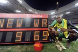 Usain Bolt pózuje u tabule s hodnotou nového světového rekordu.