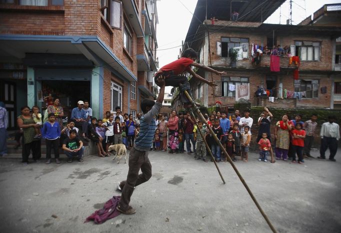 Gchan Choudhary, 17, (L) helps his younger brother Drumpal, 11, to stand on wooden stilts while performing tricks on the street of Kathmandu August 15, 2012. Gchan, Drumpal and their sister Shivani, who came to Kathmandu from India 5 years ago, earn their living by performing tricks on the streets of Kathmandu. According to Drumpal, they earn around $10 a day by performing tricks, which is not enough to feed their 10-member family living together in a small hut without a proper toilet or any basic needs. REUTERS/Navesh Chitrakar (NEPAL - Tags: SOCIETY TPX IMAGES OF THE DAY POVERTY IMMIGRATION) Published: Srp. 15, 2012, 4:24 odp.