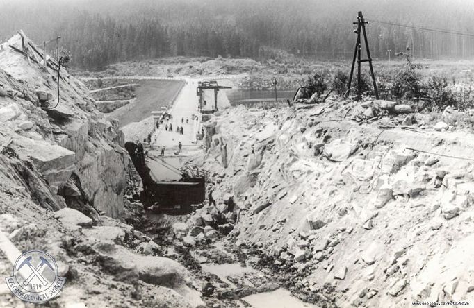 Výlom zářezu pro novou levobřežní silniční trasu navazující na hráz. Pohled k jihu, v pozadí přehrada. Snímek z roku 1959.