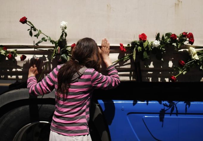 A Bosnian woman kisses one of the three trucks carrying 520 coffins of the newly identified victims of the 1995 Srebrenica massacre in front of the presidential building in Sarajevo July 9, 2012. The bodies of the recently identified victims will be transported to the memorial centre in Potocari where they will be buried on July 11 marking the 17th anniversary of the massacre in which Bosnian Serb forces commanded by Ratko Mladic killed up to 8,000 Muslim men and boys and buried them in mass graves. REUTERS/Dado Ruvic (BOSNIA AND HERZEGOVINA - Tags: ANNIVERSARY CIVIL UNREST POLITICS) Published: Čec. 9, 2012, 10:57 dop.