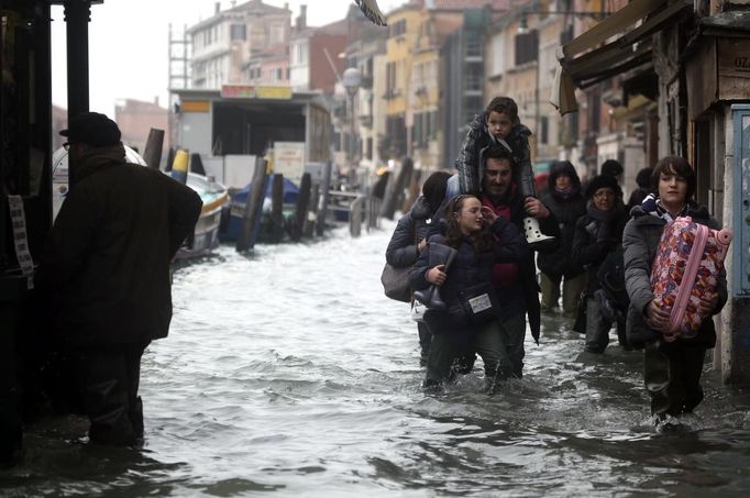 Tourists walk in a flooded street during a period of seasonal high water in Venice November 1, 2012. The water level in the canal city rose to 140 cm (55 inches) above normal, according to the monitoring institute. REUTERS/Manuel Silvestri (ITALY - Tags: ENVIRONMENT SOCIETY TRAVEL) ATTENTION EDITORS - ITALIAN LAW REQUIRES THAT THE FACES OF MINORS ARE MASKED IN PUBLICATIONS WITHIN ITALY Published: Lis. 1, 2012, 1:19 odp.