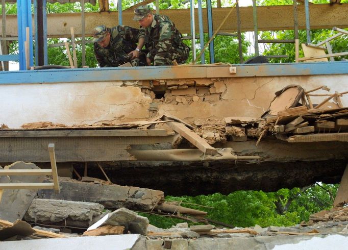 Členové čečenských bezpečnostních složek prohlížejí trosky stadionu v Grozném po explozi 9. května 2004, která zabila prezidenta Achmada Kadyrova a další osoby.