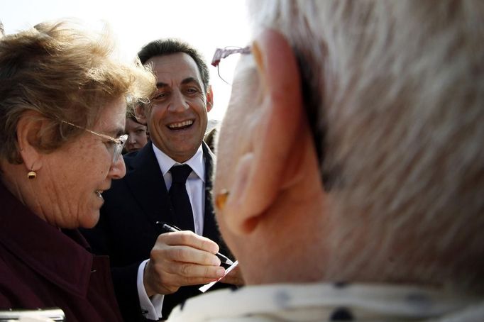 France's President and UMP party candidate for the 2012 French presidential elections Nicolas Sarkozy signs autographs for residents during a campaign visit to Valenciennes