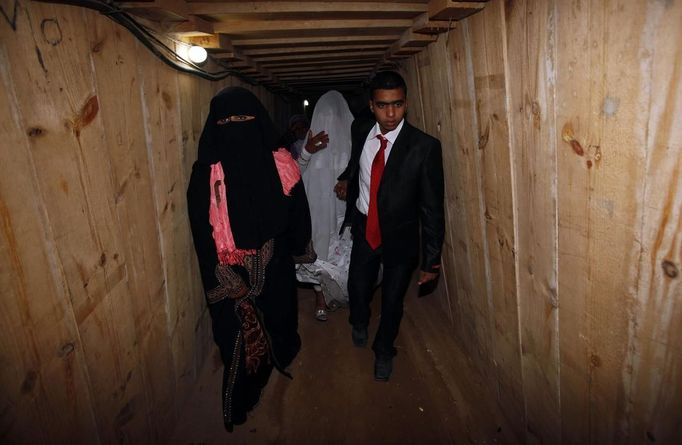 Palestinian groom Emad al-Malalha, 21, walks with Manal Abu Shanar, 17, his Egyptian bride inside a smuggling tunnel beneath the Gaza-Egypt border in the southern Gaza Strip March 21, 2013. Al-Malalha , who said that his bride was not given a permit from Egyptian authorities to enter the Gaza Strip, brought her from neighboring Egypt through a smuggling tunnel to celebrate his wedding in his native Gaza Strip. REUTERS/Ibraheem Abu Mustafa (GAZA - Tags: POLITICS SOCIETY TPX IMAGES OF THE DAY) Published: Bře. 21, 2013, 6:15 odp.