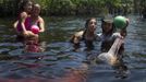 Elinei Afosno (L) carries her daughter Yasmim Vitoria Afonso, 5, who suffers from mental retardation and Igor Andrade, a physiotherapist, assists Alice Castro, 17, who suffers from mild cerebral palsy, while interacting with a dolphin during a "Bototherapy" session at Arau River in Amazon August 11, 2012. The "Bototherapy", a "Rolfing" therapeutic practice assisted by river dolphins, was developed by Andrade and the treatment is free for children from low income with disabilities or disorders. Picture taken August 11, 2012. �REUTERS/Bruno Kelly (BRAZIL - tags: - Tags: SOCIETY HEALTH) Published: Srp. 28, 2012, 12:15 dop.