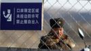 A soldier stands guard near a barbed wire fence on Hwanggumpyong Island located in the middle of the Yalu River, near the North Korean town of Sinuiju and the Chinese border city of Dandong, March 29, 2013. China called for an easing of tensions on Friday as North Korea put its missile units on standby to attack U.S. military bases in South Korea and the Pacific after the United States flew two nuclear-capable stealth bombers over the Korean peninsula. The Chinese characters on the signboard read "restricted areas in ports, entry not allowed if no border permission." REUTERS/Jacky Chen