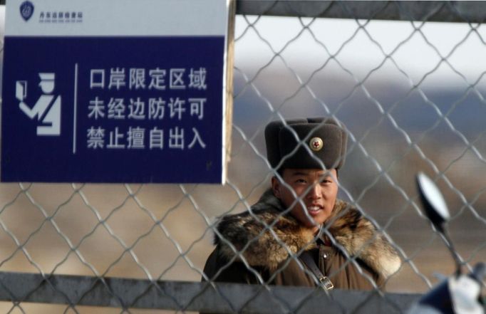 A soldier stands guard near a barbed wire fence on Hwanggumpyong Island located in the middle of the Yalu River, near the North Korean town of Sinuiju and the Chinese border city of Dandong, March 29, 2013. China called for an easing of tensions on Friday as North Korea put its missile units on standby to attack U.S. military bases in South Korea and the Pacific after the United States flew two nuclear-capable stealth bombers over the Korean peninsula. The Chinese characters on the signboard read "restricted areas in ports, entry not allowed if no border permission." REUTERS/Jacky Chen