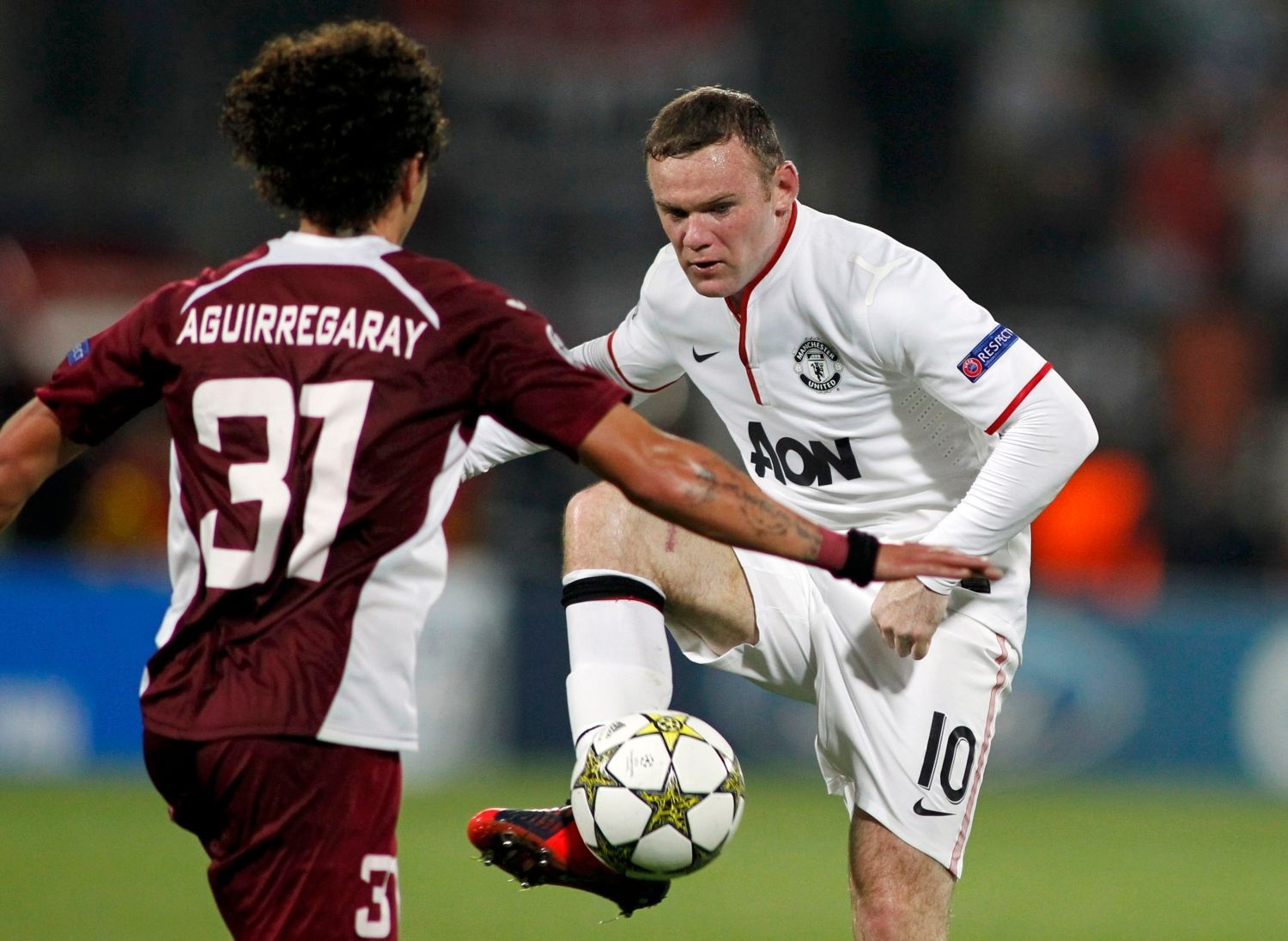 Fotbalista Manchesteru United Wayne Rooney v souboji s Matiasem Aguirregarayem z Kluže v utkání Ligy mistrů 2012/13.