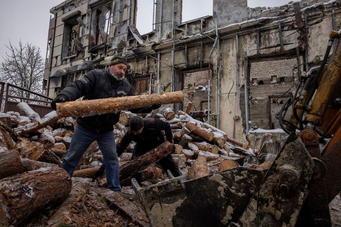 Men pile up wood for homes that are left without heating outside a courthouse that was destroyed by an airstrike, in the frontline town of Lyman, amid Russia's attack on