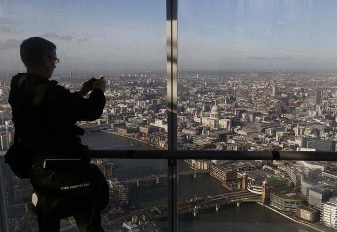 ATTENTION EDITORS - EMBARGOED FOR PUBLICATION TO 00:01 GMT JANUARY 11, 2013 A man takes a photograph St Paul's cathedral and the Thames River from a window in The View gallery at the Shard, western Europe's tallest building, in London January 9, 2013. The View, the public viewing deck accessible by high speed elevators on the 309 metre (1013 feet) Shard building, opens on February 1. Picture taken January 9, 2013. REUTERS/Luke Macgregor (BRITAIN - Tags: TRAVEL CITYSCAPE) TEMPLATE OUT Published: Led. 10, 2013, 12:08 odp.