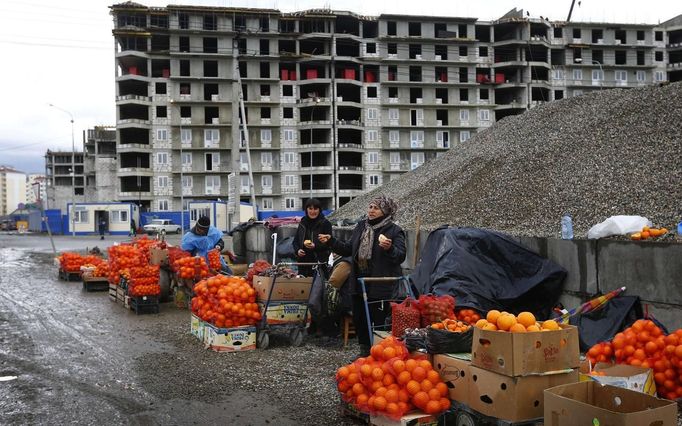 Women sell fruits and nuts near a construction site for the Sochi 2014 Winter Olympics within the perimeters of the Olympic Park in Adler, near Sochi February 18, 2013. Although many complexes and venues in the Black Sea resort of Sochi mostly resemble building sites that are still under construction, there is nothing to suggest any concern over readiness. Construction will be completed by August 2013 according to organizers. The Sochi 2014 Winter Olympics opens on February 7, 2014. REUTERS/Kai Pfaffenbach (RUSSIA - Tags: CITYSCAPE BUSINESS CONSTRUCTION ENVIRONMENT SPORT OLYMPICS) Published: Úno. 18, 2013, 6:20 odp.