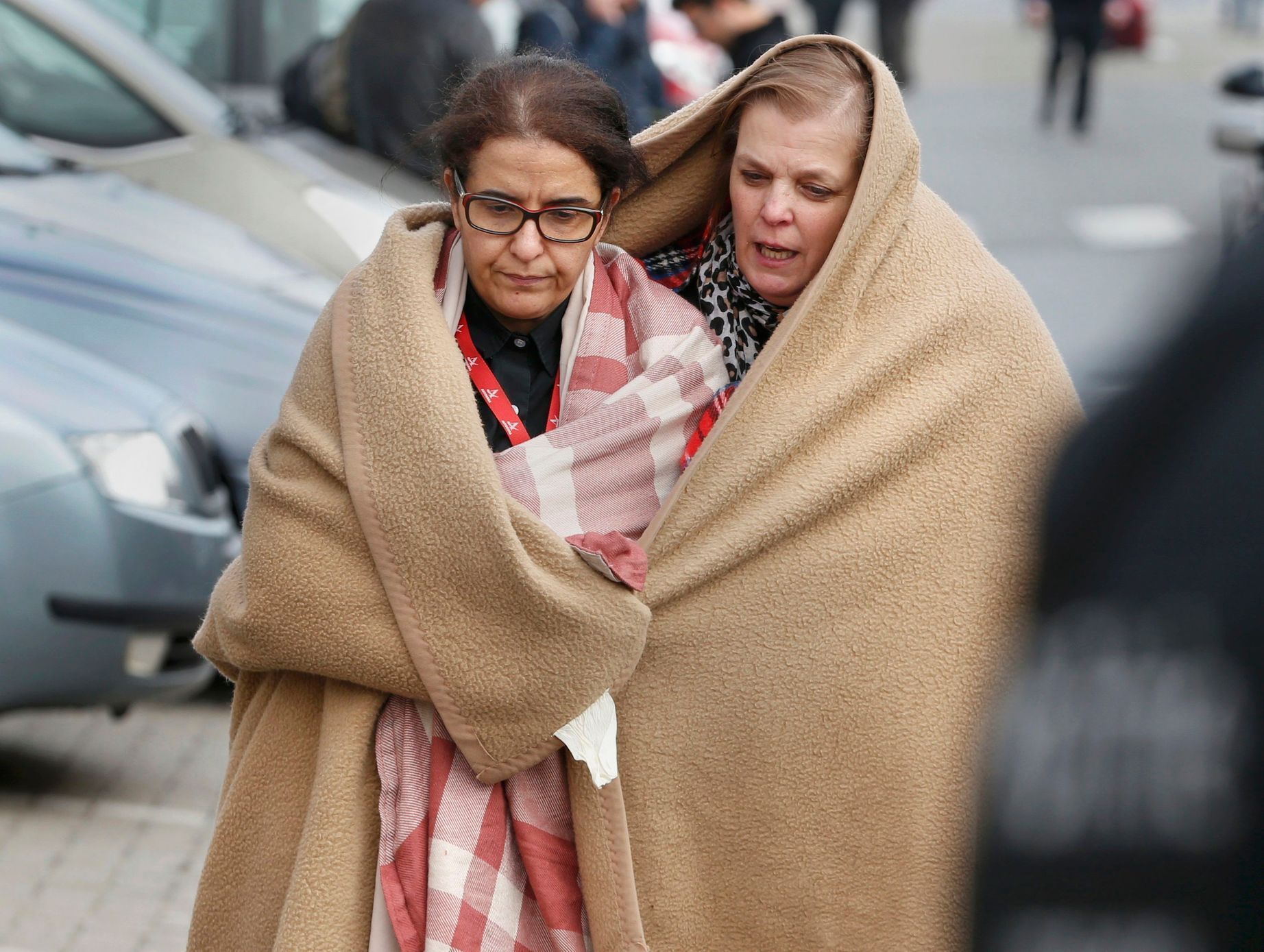 Belgie Brusel terorismus People wrapped in blankets leave the scene of explosions at Zaventem airport near Brussels, Belgium