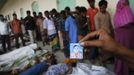 A relative holds a picture of a garment worker who is missing, in front of the remains of people who died inside the rubble of the collapsed Rana Plaza building, in Savar, 30 km (19 miles) outside Dhaka April 25, 2013. The number of people killed by the collapse of a building in Bangladesh's capital rose to 147 overnight and the death toll could climb further because many people are still trapped inside, Dhaka's district police chief told Reuters on Thursday. REUTERS/Andrew Biraj (BANGLADESH - Tags: DISASTER) Published: Dub. 25, 2013, 3:31 dop.