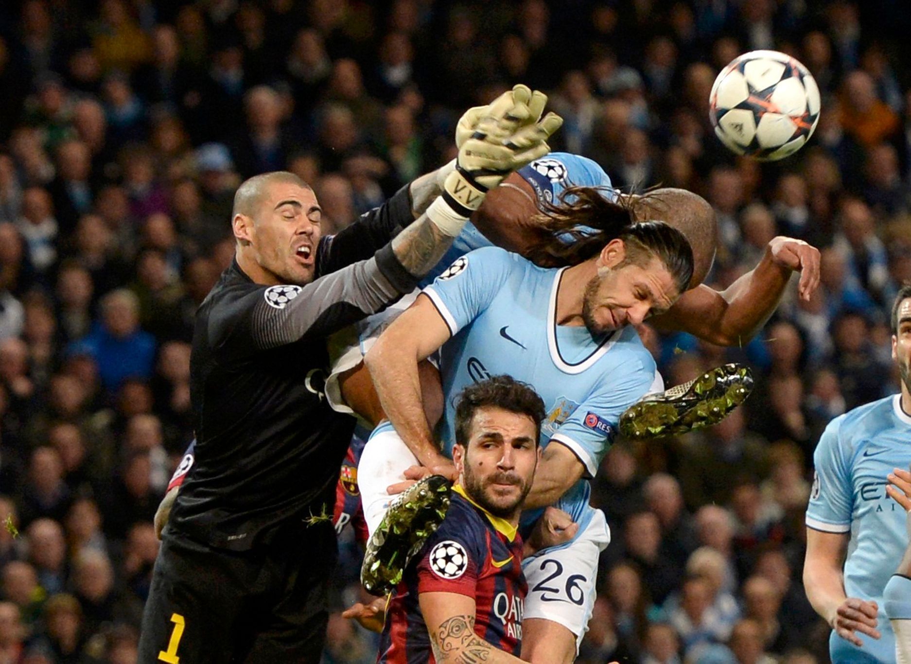 Barcelona's goalkeeper Valdes punches the ball past Barcelona's Fabregas and Manchester City's Kompany and Demichelis during their Champions League round of 16 first leg soccer match against Barcelona