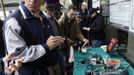 People stand around a table that a store has placed outside with power bars for cell phone charging, in the aftermath of Hurricane Sandy in New York November 1, 2012. The subway has been put back on limited service. Rescuers searched flooded homes for survivors, drivers lined up for hours to get scarce gasoline and millions remained without power on Thursday as New York City and nearby towns struggled to recover from Sandy, one of the biggest storms ever to hit the United States. REUTERS/Carlo Allegri (UNITED STATES - Tags: ENVIRONMENT DISASTER ENERGY BUSINESS TELECOMS) Published: Lis. 1, 2012, 9:08 odp.