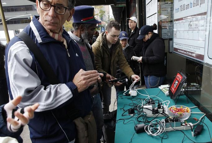 People stand around a table that a store has placed outside with power bars for cell phone charging, in the aftermath of Hurricane Sandy in New York November 1, 2012. The subway has been put back on limited service. Rescuers searched flooded homes for survivors, drivers lined up for hours to get scarce gasoline and millions remained without power on Thursday as New York City and nearby towns struggled to recover from Sandy, one of the biggest storms ever to hit the United States. REUTERS/Carlo Allegri (UNITED STATES - Tags: ENVIRONMENT DISASTER ENERGY BUSINESS TELECOMS) Published: Lis. 1, 2012, 9:08 odp.