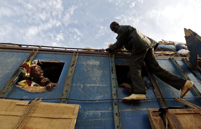 A woman looks out of the bus window at a man climbing on the outside, in Sevare January 26, 2013. REUTERS/Eric Gaillard (MALI - Tags: CIVIL UNREST SOCIETY TPX IMAGES OF THE DAY) Published: Led. 26, 2013, 6:40 odp.