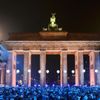 People wait in front of the stage in front of the Brandenburg Gate next to part of the installation 'Lichtgrenze' (Border of Light) in Berlin