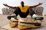 Jamaičan Usain Bolt pózuje před Národním stadionem. Nejrychlejší sprinter světa poběží v Pekingu ve zlatých tretrách, které leží před ním.