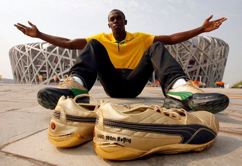 Jamaičan Usain Bolt pózuje před Národním stadionem. Nejrychlejší sprinter světa poběží v Pekingu ve zlatých tretrách, které leží před ním.