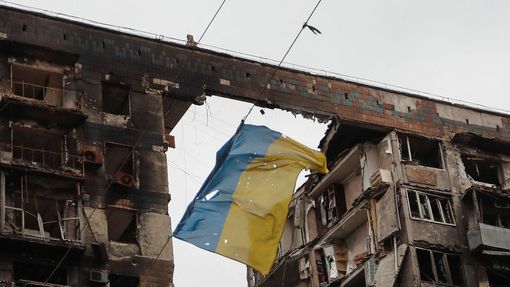 Ukrajinská vlajka pověšená na drátu mezi částmi budovy v Mariupolu zničené bombardováním.
