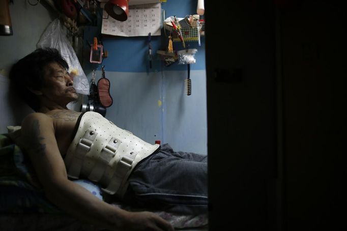 Kam Chung, 49, wears a brace as he rest in a wooden box that he lives in Hong Kong October 9, 2012. In Hong Kong's middle-class residential area, short distance from its shopping and financial districts, 24 people live in these wooden boxes, or "coffin homes", packed in a single apartment of little over 50 square meters. Its residents pay 1450 Hong Kong dollars ($180) for their living space built of wooden panels of 2 meters by 70 cm. To maximize income from the rent in central Hong Kong landlords build "coffin homes", nicknamed due to their resemblance to real coffins. Space has always been at a premium in Hong Kong where developers plant high-rises on every available inch. REUTERS/Damir Sagolj (CHINA - Tags: SOCIETY REAL ESTATE BUSINESS TPX IMAGES OF THE DAY) Published: Říj. 9, 2012, 1:36 odp.