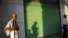 Mahesh Chaturvedi (L), 63, who dresses up like Mahatma Gandhi, stands outside a closed shop in New Delhi September 28, 2012. Chaturvedi says that the soul of Gandhi resides in him and he has been sent to continue the work of Father of the Nation. After his self proclaimed transformation in 2002 as Gandhi, Chaturvedi has been travelling extensively and plays up to his startling resemblance to Gandhi at protests and demonstrations. Picture taken September 28, 2012. REUTERS/Mansi Thapliyal (INDIA - Tags: SOCIETY) Published: Lis. 26, 2012, 3:54 dop.