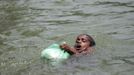 A boy, who is affected by flood swims with a bag of food distributed by local organizations in Sylhet June 30, 2012. At least 100 people have died and 250,000 left stranded by flash floods and landslides in Bangladesh set off by the heaviest rain in years. The low-lying and densely populated country, which is in its wet season, has been battered by five days of torrential downpours. REUTERS/Andrew Biraj (BANGLADESH - Tags: SOCIETY DISASTER ENVIRONMENT) Published: Čer. 30, 2012, 4:08 odp.