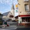 A woman crosses the street near a church which was rebuilt under the Marshall Plan along with the rest of the Normandy town of Aunay-Sur-Odon
