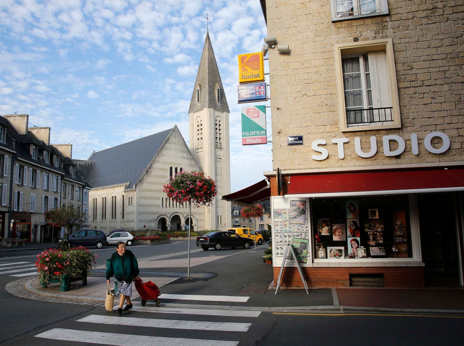 A woman crosses the street near a church which was rebuilt under the Marshall Plan along with the rest of the Normandy town of Aunay-Sur-Odon