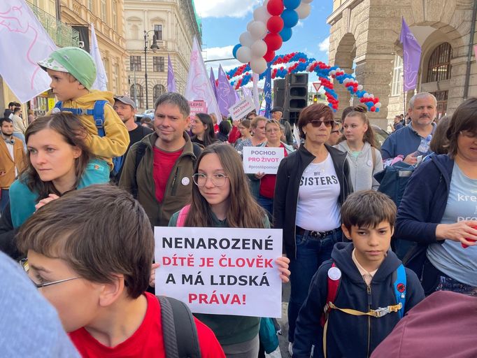 Mezi zhruba několika sty účastníky Pochodu pro život jsou především rodiny s dětmi, lidé mají vlajky s nápisy "Nesoudíme, pomáháme" či "Jsme kreativní, jsme pro život".