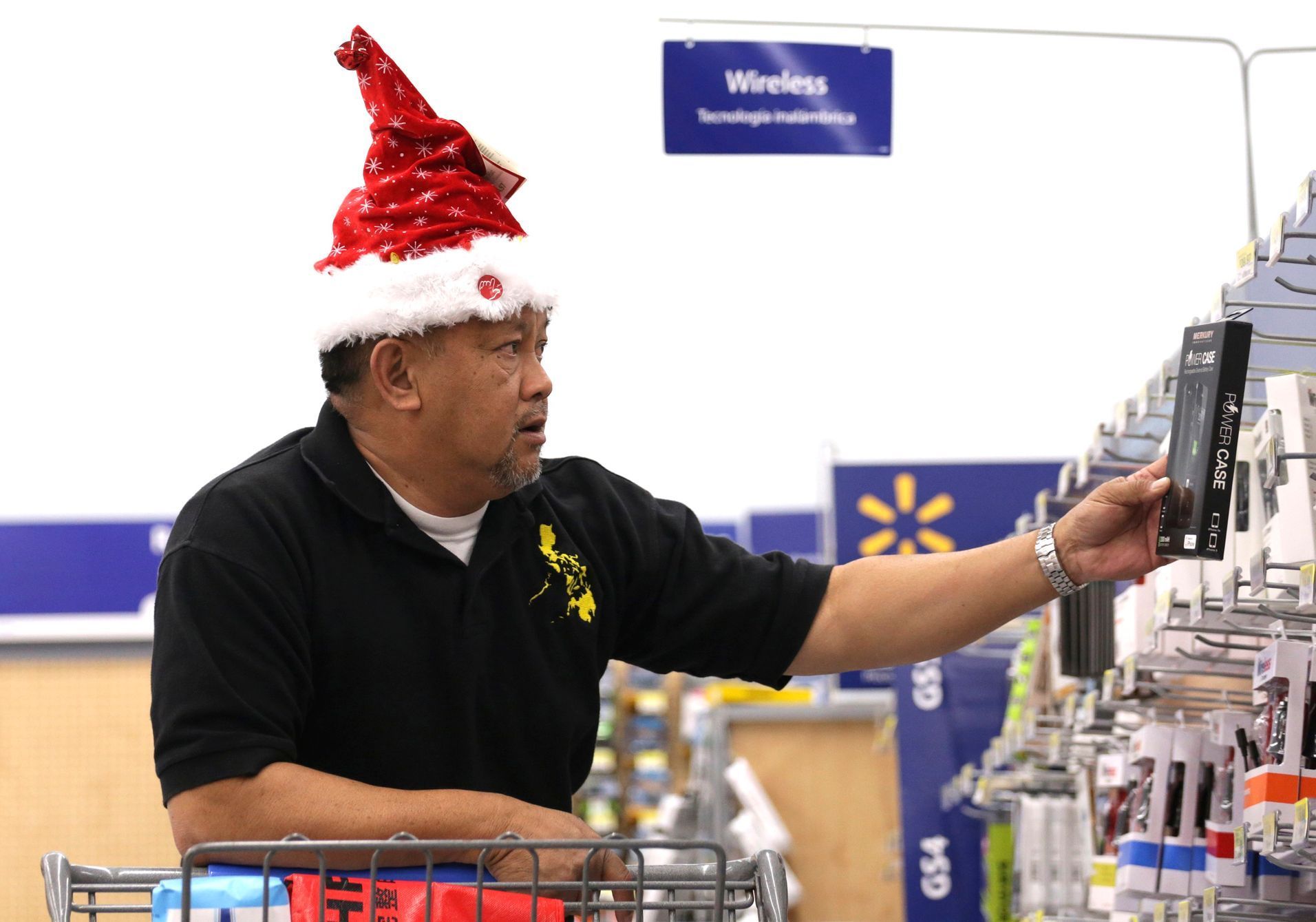 Policarpio looks at a mobile phone power case at Walmart as the store prepares for Black Friday in Los Angeles