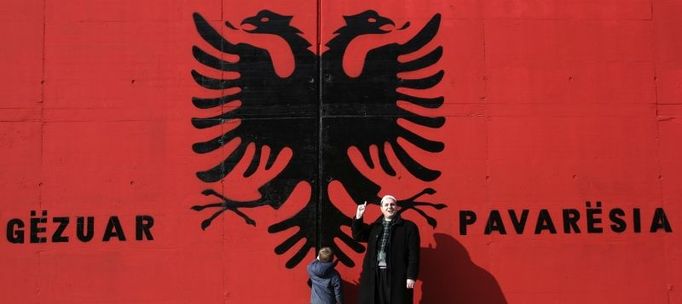 Kosovo Albanians stand in front of a giant Albanian flag with the words "Happy Independence" painted on a wall in the south Kosovo town of Kacanik February 11, 2008. The European Union is set to complete authorisation of a big supervisory mission in Kosovo this week, just before the territory is expected to declare independence from Serbia, diplomats and EU officials said. REUTERS/Hazir Reka (SERBIA)