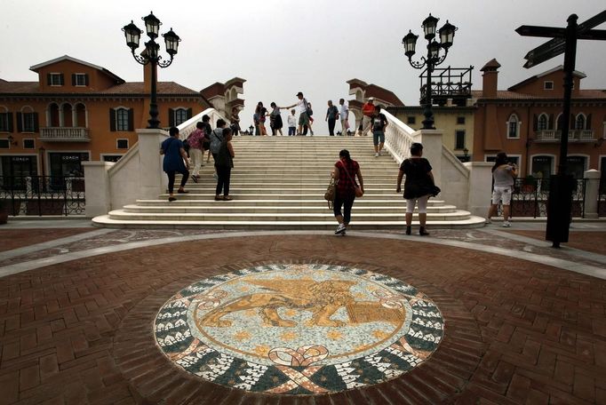 A Venetian Lion emblem adorns the footpath as pedestrians walk across a bridge over a canal that flows through the center of the Florentia Village in the district of Wuqing, located on the outskirts of the city of Tianjin June 13, 2012. The shopping center, which covers an area of some 200,000 square meters, was constructed on a former corn field at an estimated cost of US$220 million and copies old Italian-style architecture with Florentine arcades, a grand canal, bridges, and a building that resembles a Roman Coliseum. REUTERS/David Gray (CHINA - Tags: SOCIETY BUSINESS) Published: Čer. 13, 2012, 5:11 odp.