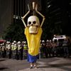 Military policemen stand in a line behind a demonstrator wearing the figure of a skeleton holding up a trophy representing that of the FIFA World Cup during a protest against the 2014 World Cup, in Sa